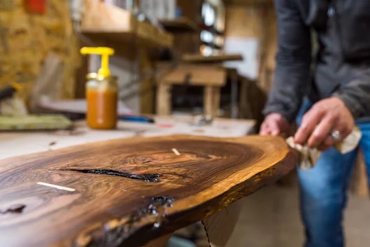Polishing wood in workshop to complete custom table live edge wood design slab polishing